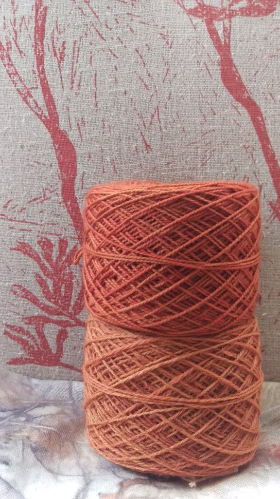 Two balls of yarn wound into cakes in two shades of orange. 
